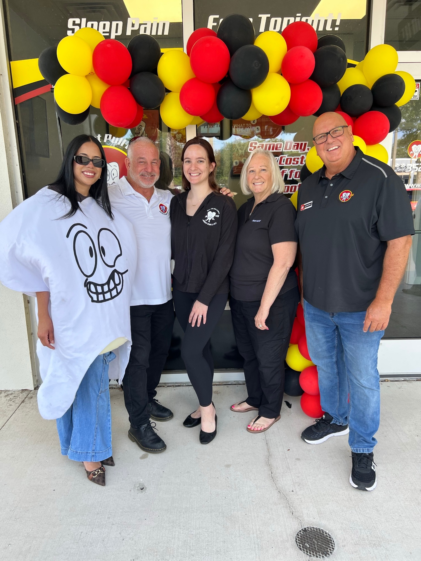 Team photo with a patient in a Just Pull It cape at the Lutz grand opening
