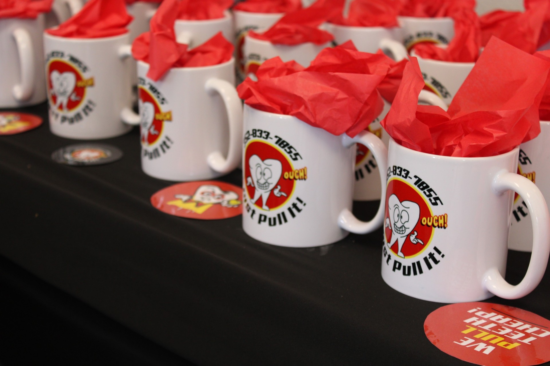 Just Pull It branded mugs with red tissue paper as grand opening gifts