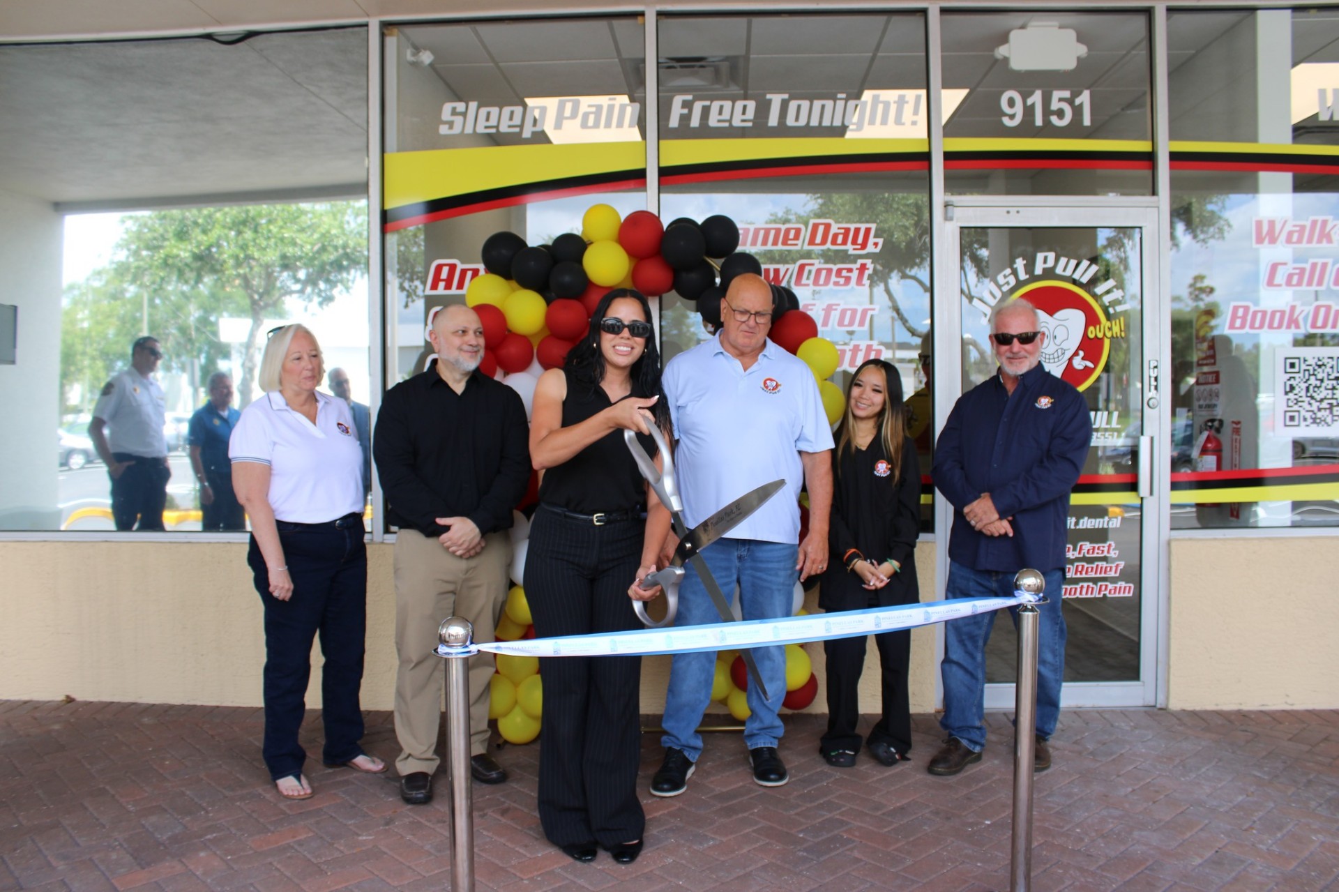 Ribbon cutting with giant scissors outside the Pinellas Park storefront